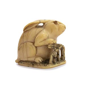 A HORN INLAID IVORY NETSUKE OF A RABBIT AND ... 