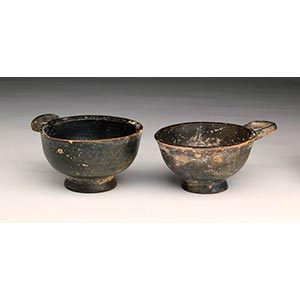 Two Etruscan one-handled black-glazed cups, ... 